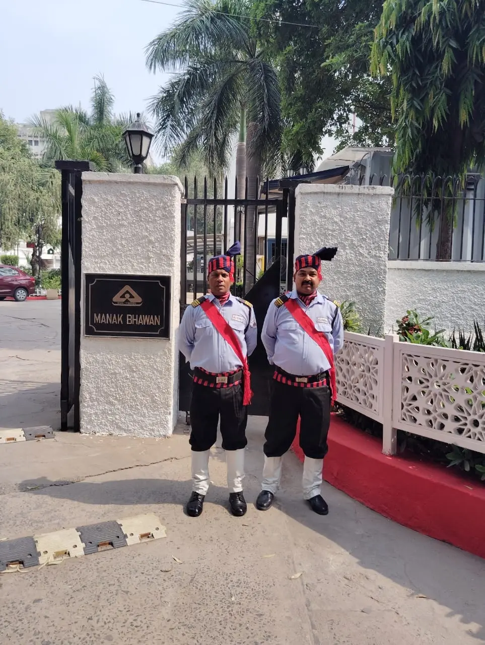 Two SMSA guards in ceremonial uniform at a gated building entrance