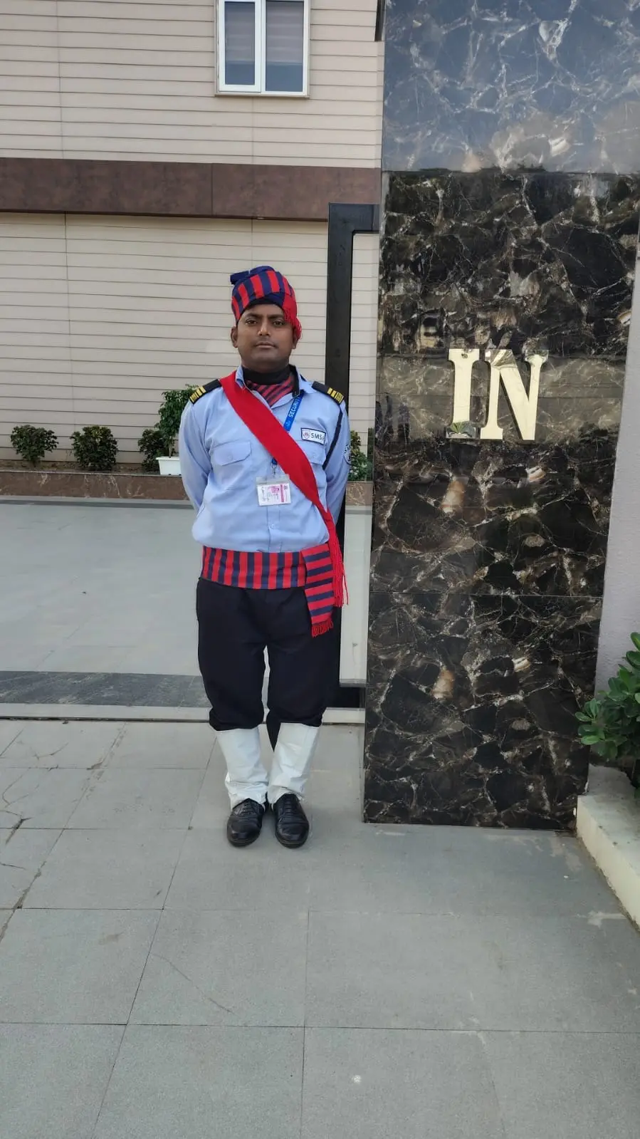 An SMSA guard standing at attention beside the IN sign of a gated entrance