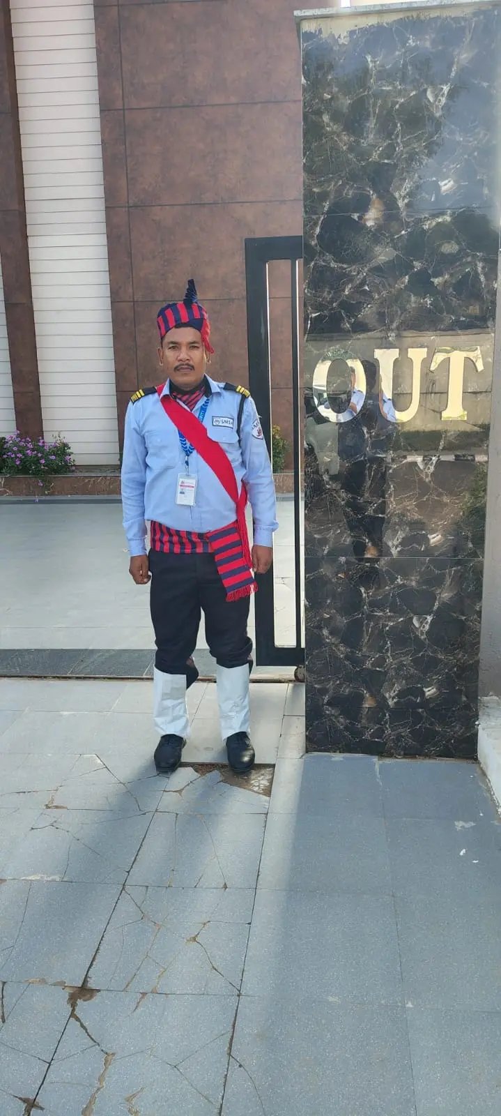 An SMSA guard standing at attention beside the OUT sign of a gated entrance