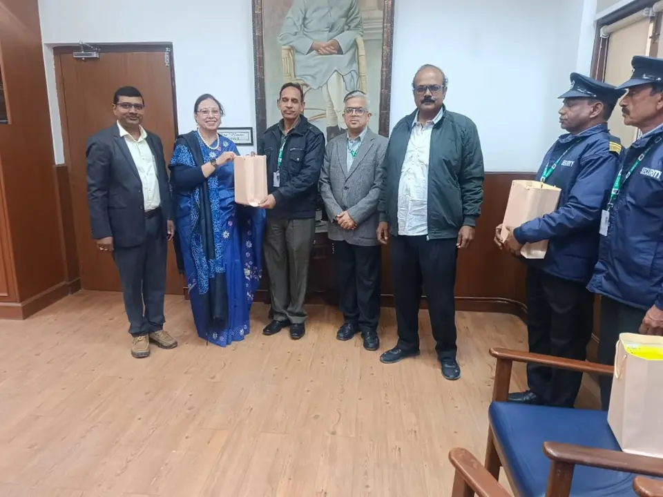 Principal and a college official presenting a gift bag to a security supervisor