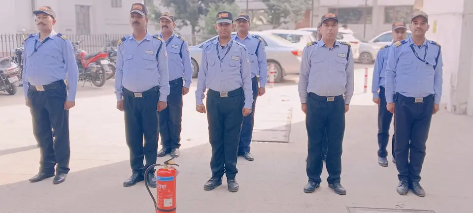 Security guards standing in formation outdoors with a fire extinguisher in the foreground