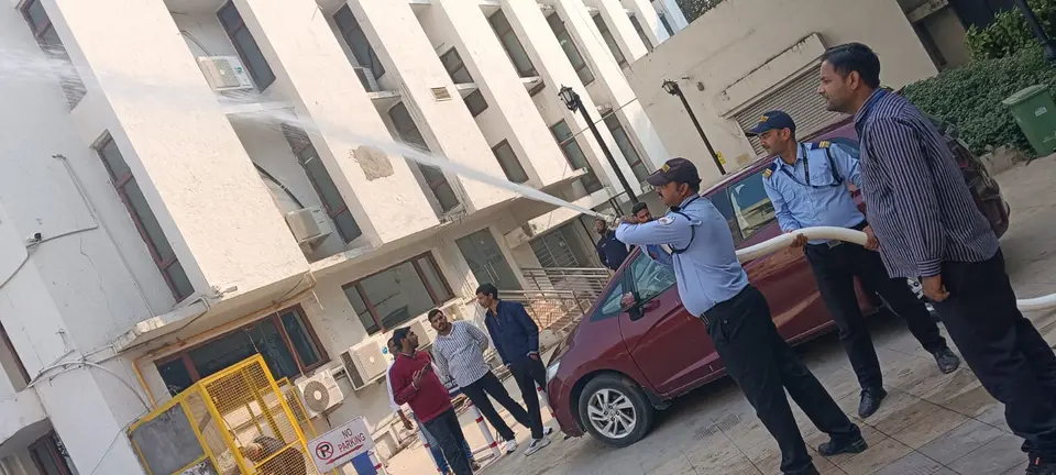 Security personnel spraying a high-pressure water stream towards a building facade during a drill