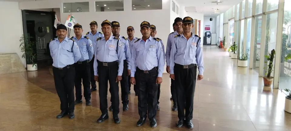 SMSA guards assembled in rows in a glass-fronted lobby with a flag in the background