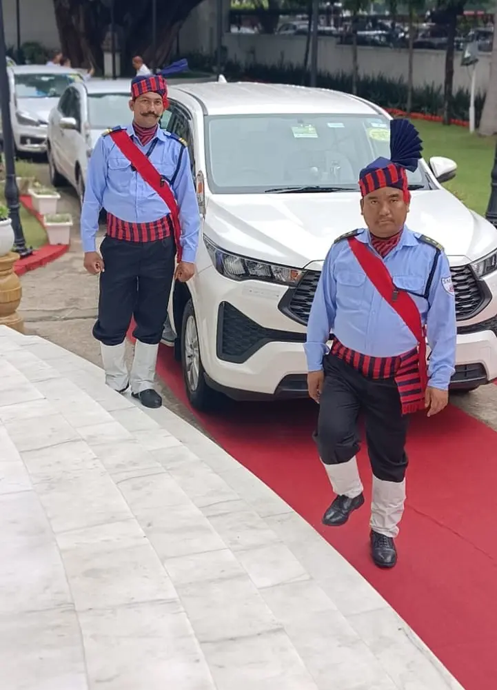 Two security guards in ceremonial dress walking down steps with a red carpet