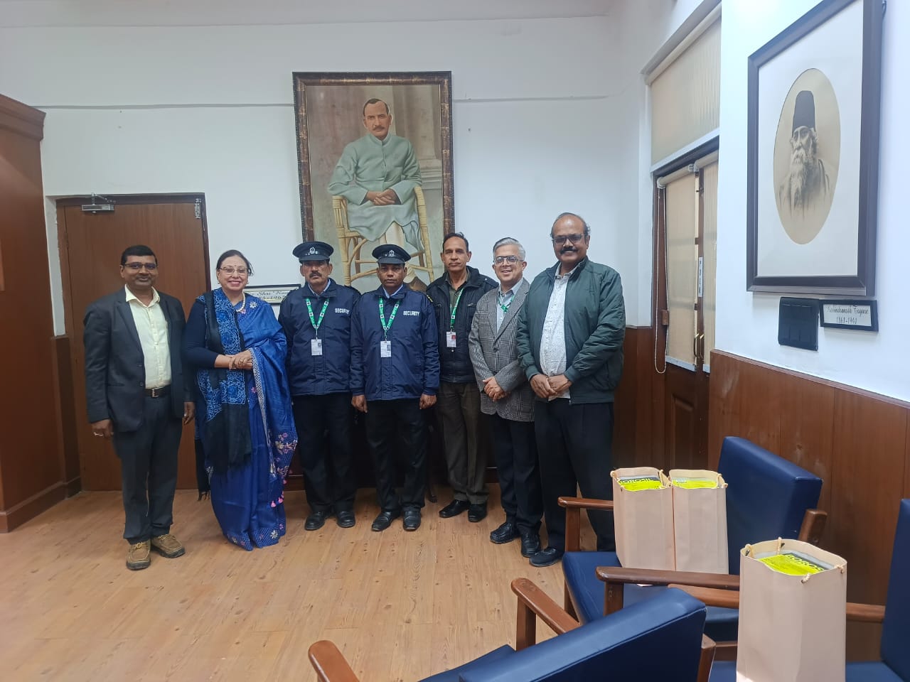Group photograph of the Principal, college officials, and security personnel in an administrative office